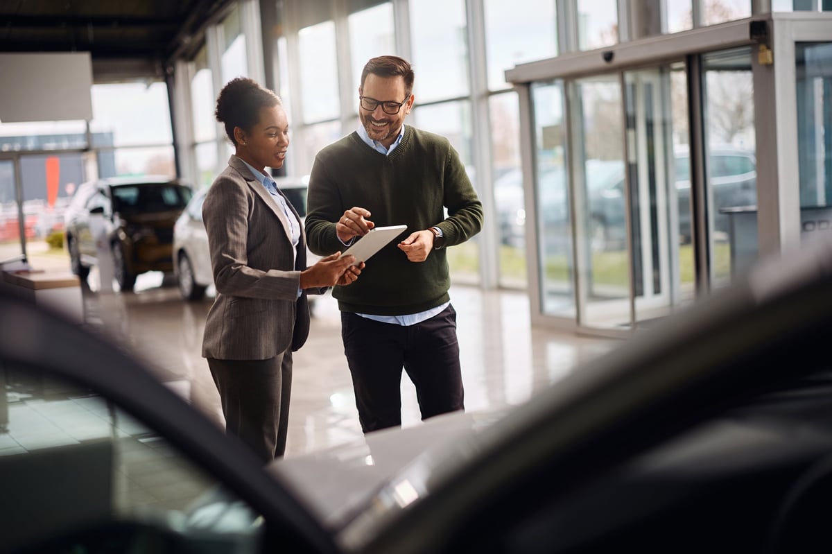Saleswoman helping customer at car dealer